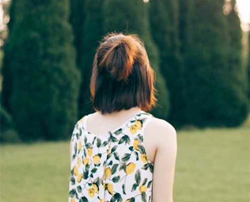 The back of a young woman wearing a floral print top looking away