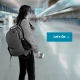 Young woman in an airport with backpack and "Let's Go" button